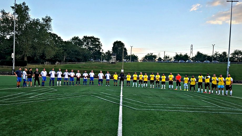 Players from both teams and the match officials standing shoulder to shoulder along the halfway line for a moment of silence at dusk